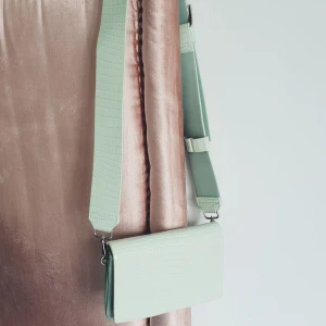 Hansväska - Trendig mint grön hansväxa i "ormmönster" med 4 fack perfekt väska för smågrejer, annväd 1 gång säljer för det inte riktigt är min stil och kom aldrig till använd, köpt på Åhléns för 400 kr 