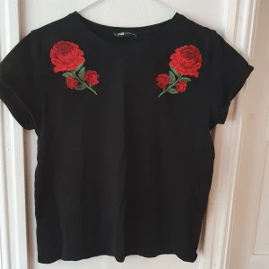 Svart tshirt med rosor - Svart t-shirt med röda rosor från New yorker. Använd 1-2 gånger så som ny ⭐ Storlek M men väldigt liten. Ganska kort så nästan en croptop. Säljs då den ej kommer till användning ⭐ Kontakta vid frågor/intresse 💜 frakt inräknad