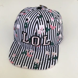Keps🧢💗 - Snygg svart och vit randig keps med texten ”LOL” och några blommor och blad på.💗🤗 Aldrig använd🤩 