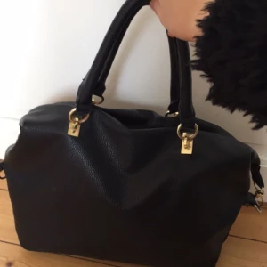  - Svart väska med guldiga detaljer. Går precis ner ett A4 i den. 