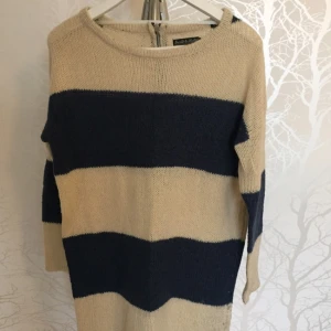  - Stockad tröja perfekt inför vintern. Beige och mörkblå, randig och med dragkedja hela vägen baktill. 14 % ull :).   Tar endast swish eller kontanter. 