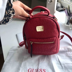  - Splitterny ryggsäck från Guess, går även att bära i handen. Superfin röd färg och aldrig använd, därav är innehållet kvar. Påse medföljer. Inköpt för ca 1300kr 
