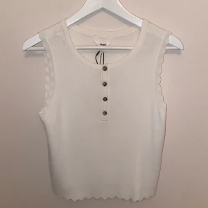 Gulligt oanvänt linne - Säljer ett supergulligt oanvänt linne med lappen kvar från Object! Linnet är ribbat med små knappar fram och gulliga vågiga kanter! Skriv vid frågor✨☺️