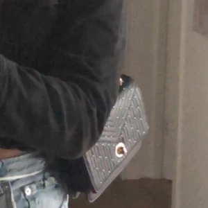 Väska  - Snygg väska i svart skinnimitation och med guldärgade detaljer. I väskan finns ett smidigt fack. 