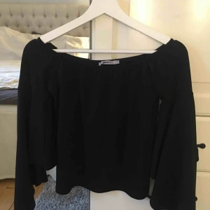  - Svart off shoulder topp från Gina med flare armar. Sitter superfint på