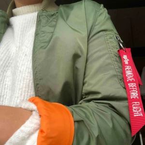  - Grön Alpha Industries jacka, med orange insida. storlek M men lite liten i storleken. Köparen står för frakt