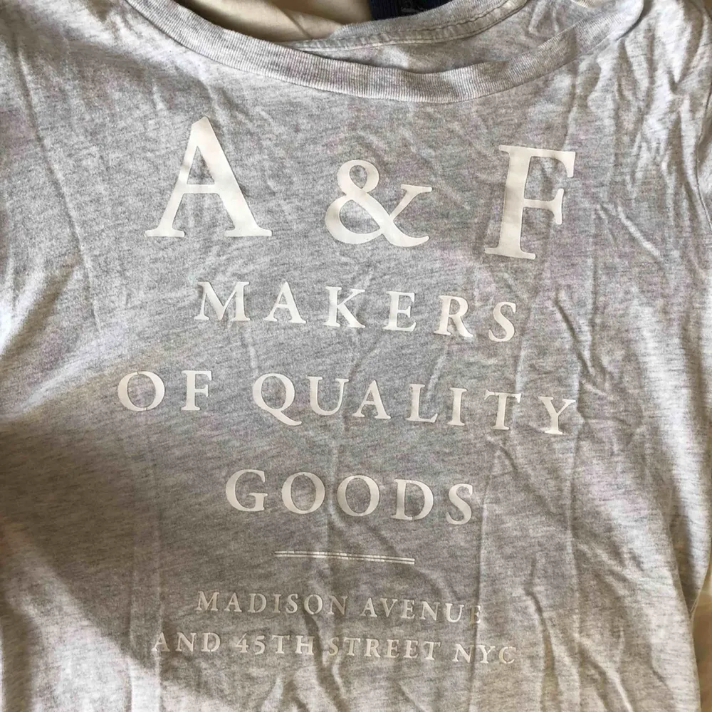 Grå t-shirt från Abercrombie and Fitch. Använd typ 3 gånger, så bra skick. På framsidan står det en text i vitt.  Storlek S, köparen står för frakten:). T-shirts.