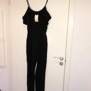  - Jumpsuit från Bikbok med lapp kvar. Halvlös modell med resår i midjan och smala justerbara band. Lapp kvar, aldrig använd. Materialet är glansigt/silke. 