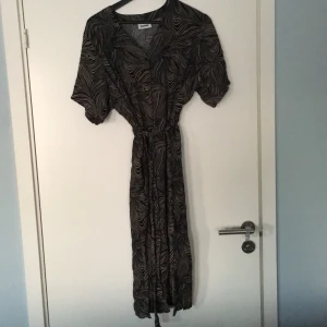 Weekday mönstrad klänningen knytning i midjan  - Weekday klänning med knytning i midjan. Mönstrad i svart och beige. Ingen storlekslapp men tror det är en medium. Använts sparsamt, lös och bekväm i passformen. 