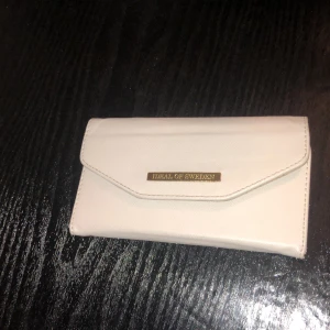 Mobil plånbok  - En grå mobil plånbok med magnet till iPhone 6,7,8. Går att enkelt tabort från mobilen. Bandet till handleden är borta. Använd men hel och fin.