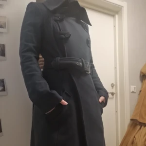 Marinblå kappa från Patrizia Pepe - Säljer en superfin kappa från Patrizia Pepe. Köpt begagnad,aldrig använd av mig. Strl 36 (enligt förra ägaren) men kan nog passa strl 38 också 🤔 Ser felfri ut i det yttre, lagad i fodret i fickorna samt ett ställe till. Även bytt ut en knapp (som ej syns) skickar gärna fler bilder samt mått på begäran!  Nypris ca 4000kr. Mitt pris 400kr + frakt på 95kr pga tung! Självklart ok att komma med eget prisförslag. 