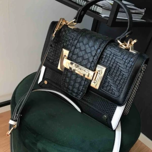  - Svart och vit väska med gulddetaljer från river island. Axelremmen går att ändra längd på. Använd 1-2 gånger :) 