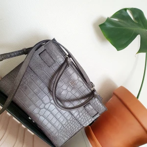 Guess-väska i fint skick! - Säljer min Guess-väska som aldrig kommit till användning. Köpte inte den ny, därav vet jag inte mycket mer om den. Fin grå färg, hel och med många fack och axelband. Köparen står för frakten, kan även hämtas i Malmö. 