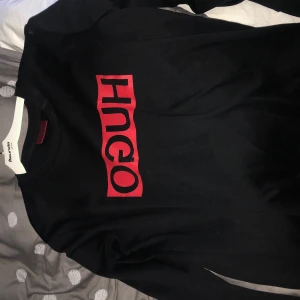 Hugo boss - En tröja från Hugo boss. Rött tryck. Nästan aldrig använd. Säljes pga för liten. Köpt på johnells. Storlek S