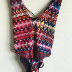 Mönstrad baddräkt  - Storlek 34. I gott skick. Fina detaljer i ryggen med snörning 