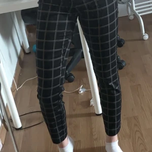 Rutiga kostymbyxor - Kostymbyxor med vita och gråa rutor. Använda ett fåtal gånger. Byxorna har resårband vid svanken och låtsasfickor där bak. Skriv för eventuella frågor osv💕 köparen står för frakt