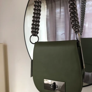 NA-KD väska - Helt oanvänd, grön NA-KD Väska med chunky chains. Väskan har en innerficka och en ytterficka på baksidan för t.ex kort. Säljes för 150kr + frakt