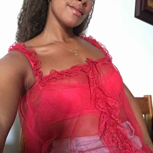  - Röd mesh topp med knappar fram dolda under volangen. Spetsvolang fram i nederkanten och ovankant. Följsamt tyg och reseår upptill för skön passform. 