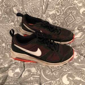 Svarta Nike gympaskor med orange detaljer. Storlek 40