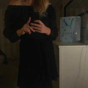 Klassisk Marinblå klänning Michael Kors - En klassisk klänning från Michael Kors. Klänningen är offshoulder men en volang upptill, kjolen är plisserad.