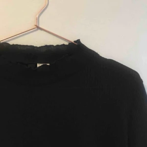 - svart polotröja med volangkanter. storlek L men passar även mindre