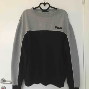 - Svart , vit och grå tjocktröja från FILA i storlek XL. Jag som är en XS har använt den som en oversized sweater. 150 kr inklusive frakt, skickar inom ett dygn! (Obs, det är inget rosa på den, utan kmr från min kamera) 
