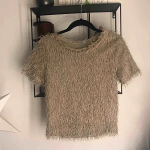  - T-shirt med fransar i sandfärgat tyg från Zara. Använd 1 gång. Tröjan är kanska kort kort och går ungefär till naveln. Passar mer som xs. (Frakt tillkommer)