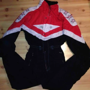  - Retro täckoverall! Varm, svart röd och vit med tajt midja. Säkert 80-90 tal. Sitter som en smäck på mig som är en M och 176 cm lång :) 