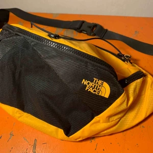 - En större The North Face fannypack. Stl L, rymlig med totalt 5 fack. Fin varm gul färg med svarta detaljer. Aldrig använd, cond därav 10/10! 