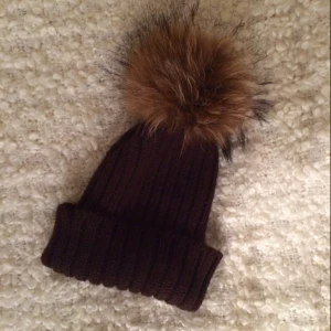  - Brun mössa med pälsboll från Hollies, knappt använd och 100% i nyskick (nypris 600kr)