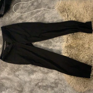 Svarta kostymbyxor  - Svarta tighta kostymbyxor med en slits jag gjort själv, från Kappahl i storlek 34