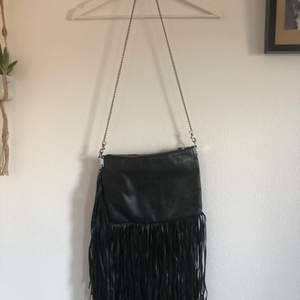 Black shoulder bag with long strips as decoration