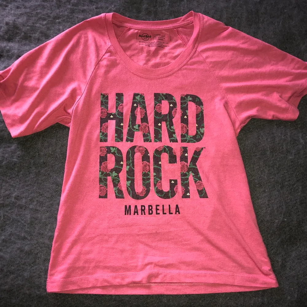 Rosa t-shirt köpt på Hard Rock Café i Marbella, Spanien. Storlek XS men passar mer som S. Cool passform, men kommer tyvärr inte till användning. Priset kan diskuteras, köpare står för frakt. Ställ gärna frågor!. T-shirts.