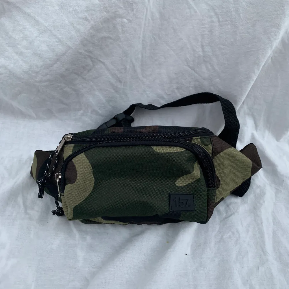 En snygg midjeväska/magväska i grön kamouflage från lager 157. Väskan är rymlig och passar väldigt bra till svart.. Väskor.