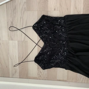 Festlig klänning från Nelly, strlk  - Svart kortklänning köpt från Nelly.com med tunna band och paljetter.