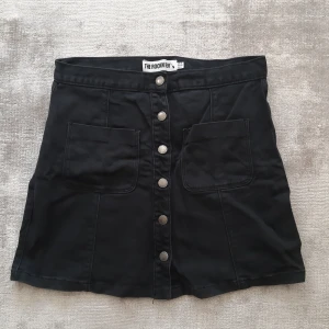 Svart jeanskjol - Svart jeanskjol, knappar framtill. I god skick men man ser på tyget att det här tvättats några gånger (tappat lite färg). Köparen står för frakt alt hämtas i Uppsala.