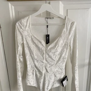 SAMMETSBODY  - Vit sammetsbody från NLY. Aldrig använd och lappar finns kvar. Möts på Södermalm och vid frakt står köparen för kostnad!