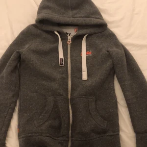 En superdry kofta  - En mörk grå superdry kofta (äkta) Storlek M men jag som har S passar den också perfekt! Köpt för 640kr
