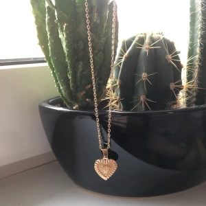 Halsband med hjärt motiv - Ett guldigt halsband med hjärt motiv. Halsbandet är oanvänt, frakten kostar 11kr oavsett hur många smycken man köper!!
