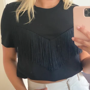 Snygg t-shirt/blus med fransar - Svart t-shirt i blusmaterial med en cool fransrad över bröstet, märket ONLY. Sparsamt använd därav nyskick. Perfekta svarta blusen för en utemiddag eller liknande. 🤩💘 Pris kan diskuteras!