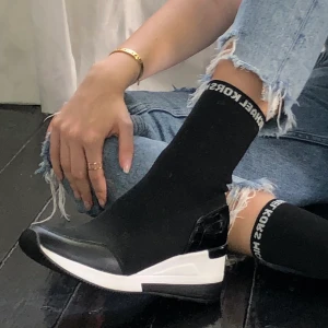 Michael kors skor - Skor i strumpmodell från michael kors med ”klack” och glittrig silverlogga i kanten. Perfekt skick utom en vit fläck på sulan (går att ta bort/måla över). Originalpris 800kr. Använda 2 gånger