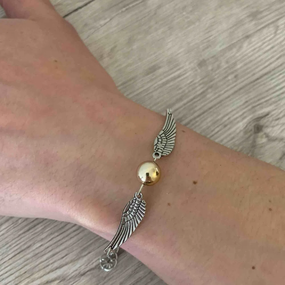 Fint silverfärgat armband med änglavingar och stor guldig pärla i mitten:) symbol från Harry Potter🥰. Accessoarer.