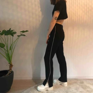  - Svara byxor med vit rand och slits i sidan från monki Använda men i bra skick