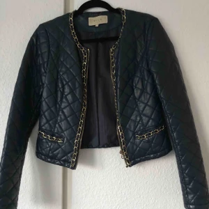  - En marinblå skinnjacka med guldiga kedjor som detaljer kring fickor och dragkedja. Jackan är av den kortare modellen. Den är inte använd på en lång period och väljer därmed att sälja den.  Köpare står för frakt. 
