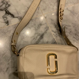 Marc Jacobs väska - Beige/kräm vit väska från Marc Jacobs, använd 2 gånger, väldigt fint skick. Dubbelfack. Guld detaljer med långt axelband 