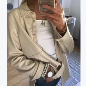 Beige skinnskjorta/jacka - beige skinnskjorta i storlek 40. sitter snyggt oversized på mig som vanligtvis har 36😇 jag har använt den som jacka, den är tunn med passar perfekt över en tjockare tröja!  knappen längst ner saknas men det är inget som stör, mycket bra skick utöver det. köpt för 479kr, säljes för 200kr, kan sänkas vid snabb affär. frakt tillkommer