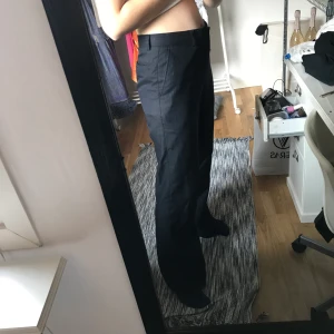 Kostymbyxor - Snygga utsvängda kostymbyxor som passar lika bra till vardags som på fest. Mörkblåa (nästan svarta) med kritstrecksränder. Jag är 168 cm och brukar ha strl. 25 i byxor och på mig är de något stora och lite långa. 
