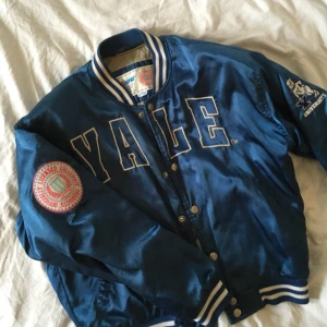  - Blå jacka i siden från Yale. ”Officielly licenced collegiate products” står det på patchen på armen - äkta vara alltså! Oversized för en s, vanlig passform för L. Får en att känna sig som i en high school-film! Fri frakt!💌