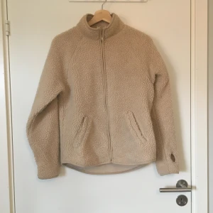 Fleece/teddy-jacka från Monki  - Beige fleece/teddy-jacka från Monki. Stl XXS, stor i storlek. Gott skick. Frakt betalas av köparen.