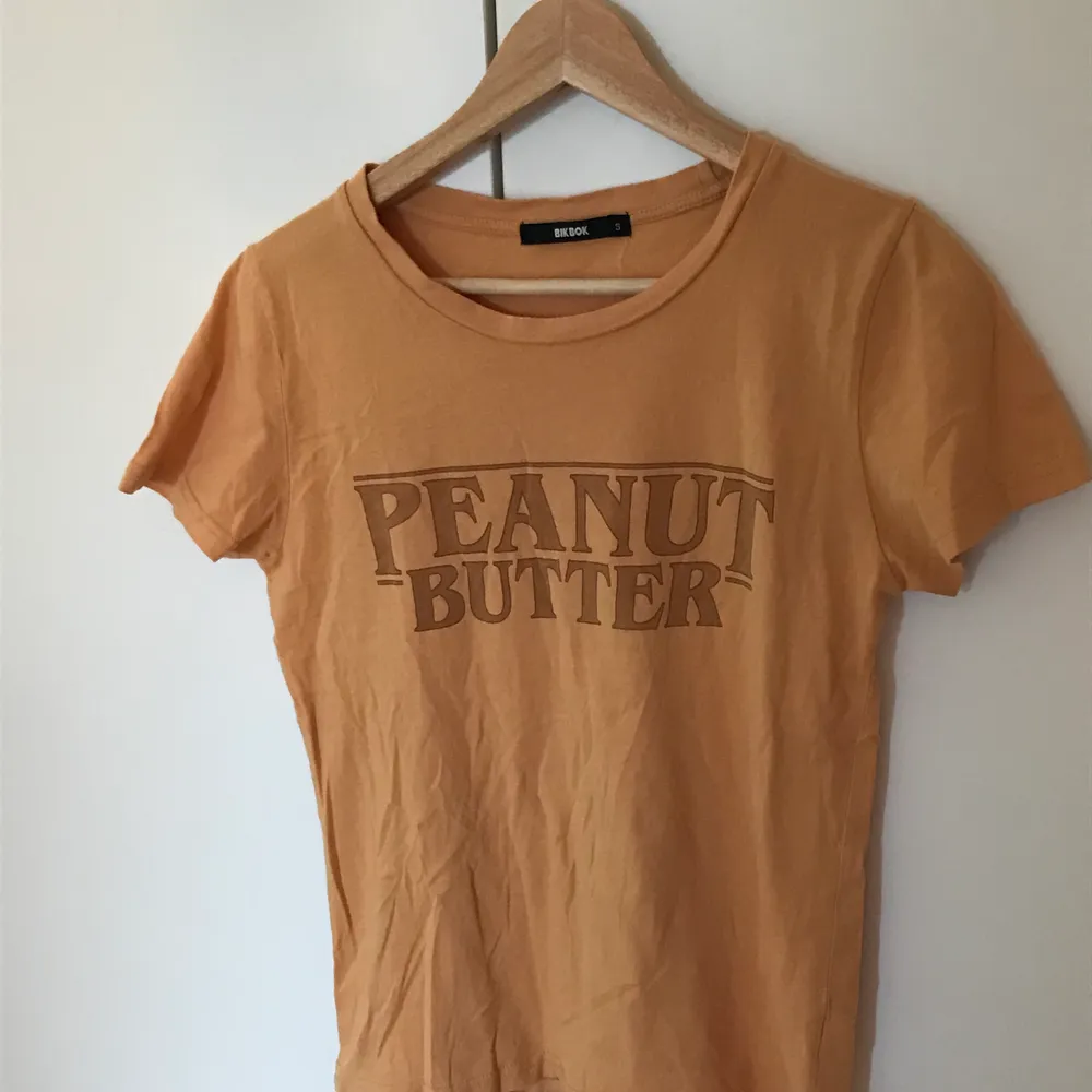 En mörkgul t-shirt som det står ”peanut butter” på, från Bikbok, i storlek S🌻 Frakt tillkommer senare💕💖. T-shirts.
